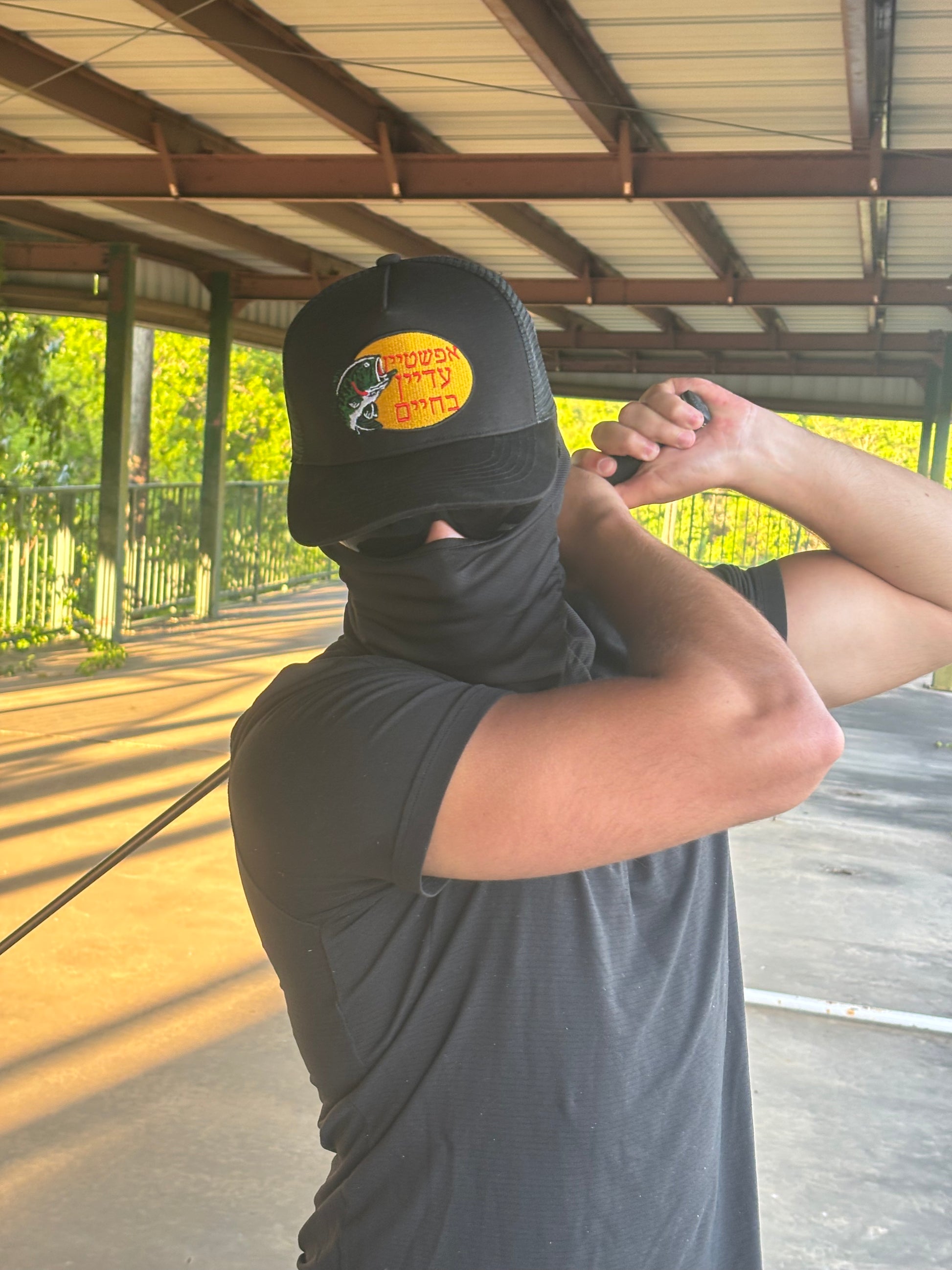 A Chud swinging a golf club at an abandoned driving range wearing the Hebrew Pro Hat