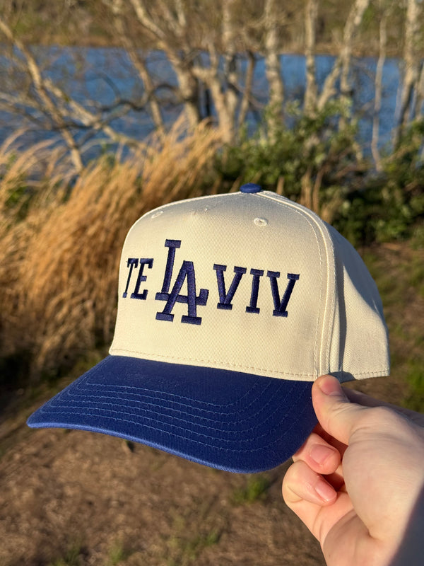 Cap with 'TE LA IVIV' text held in front of a natural landscape